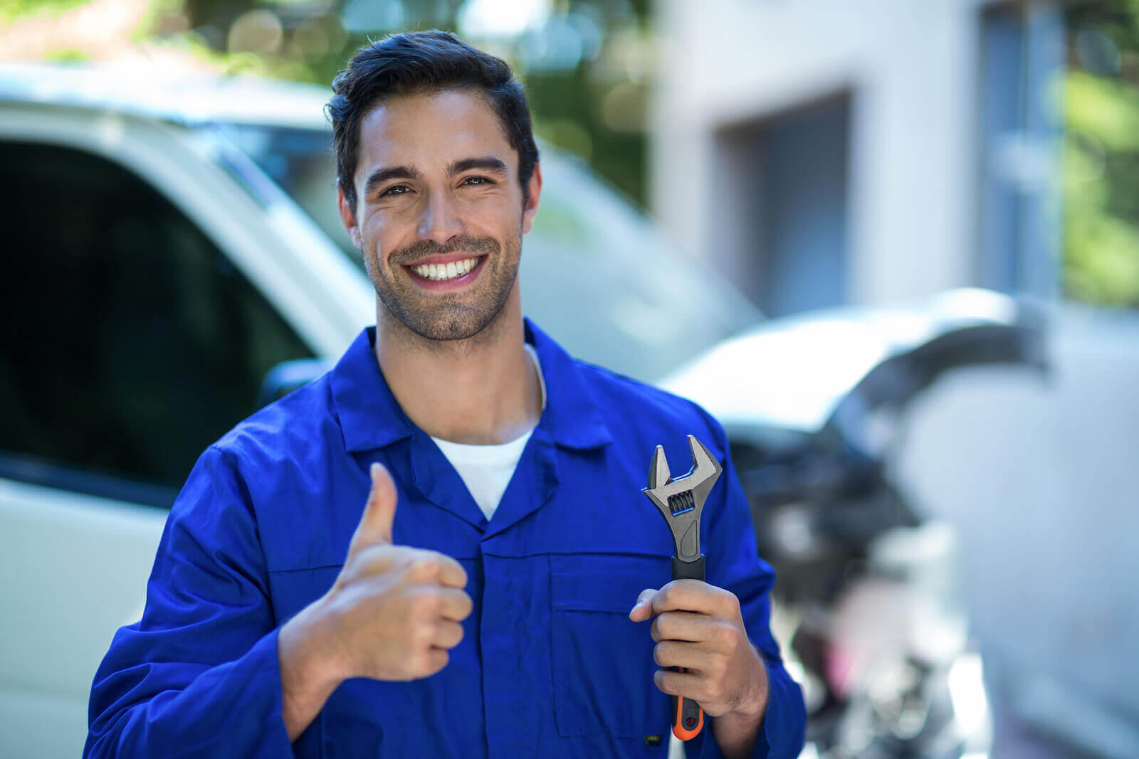 A mechanic holding a wrench giving a thumbs up